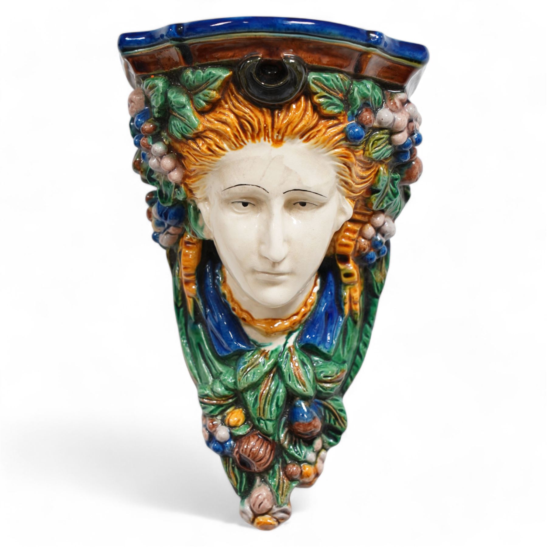 Pair of early 20th century Majolica wall brackets or corbels, formed as two ladies in high relief surrounded by fruit and foliage, on a blue and green ground H30cm 