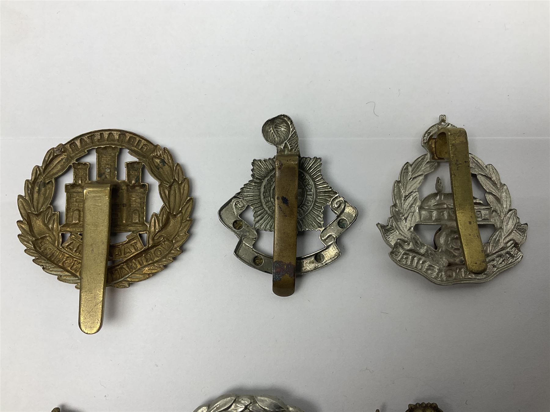 Twenty cap badges including Hertfordshire, Royal Sussex, Cambridgeshire, Hampshire, Notts and Derby, East Surrey, Herefordshire, South Lancashire, Devonshire, Bedfordshire, Durham Light Infantry etc (20)