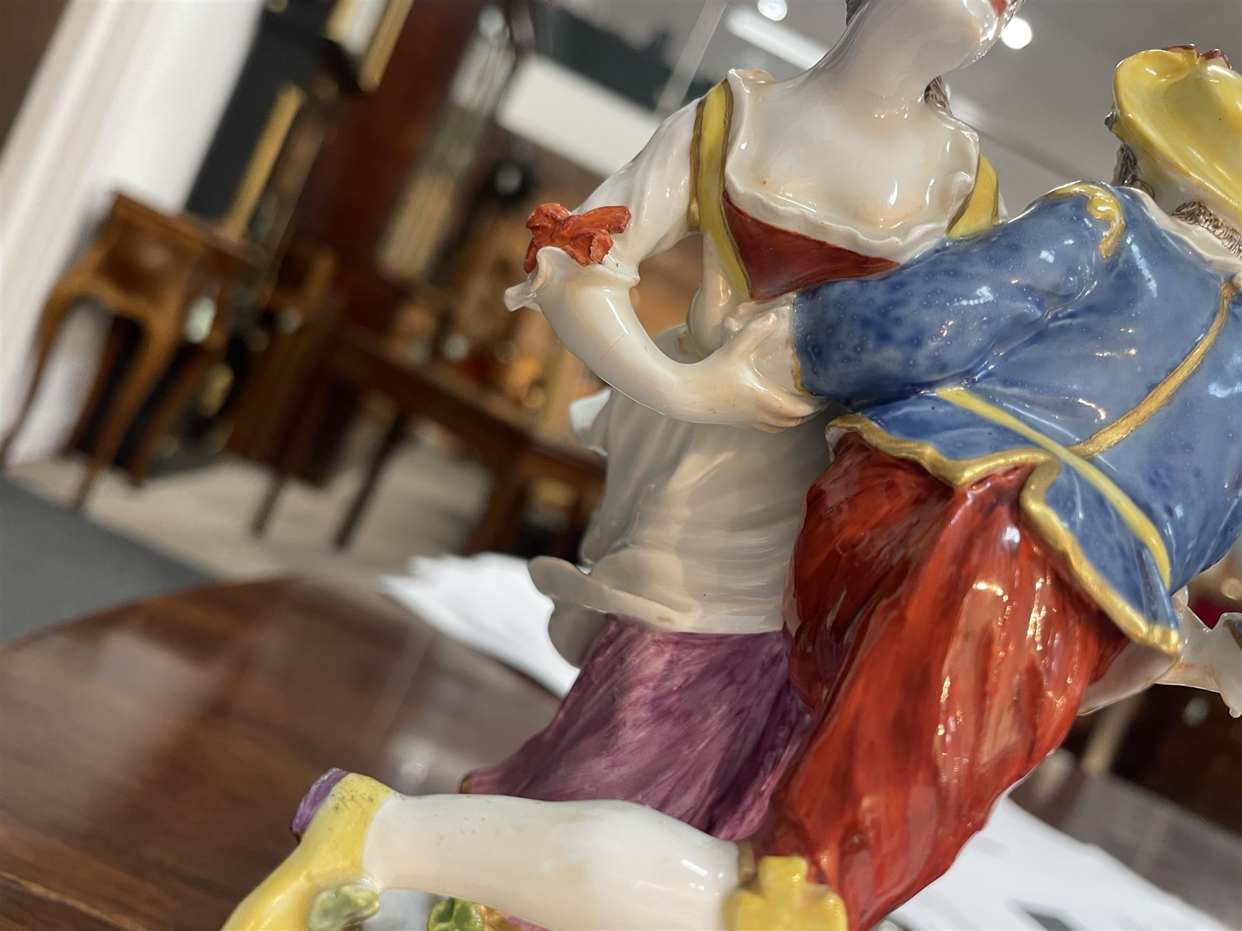 Mid 18th century Meissen figure group, The Tyrolean Dancers, circa 1740, modelled as two swirling figures with their arms linked, he in yellow hat with red rosette, blue jacket, red breeches with red rosette, and yellow shoes with green rosette, she in white blouse with red ribbons, yellow and red bodice, white apron over puce skirt and yellow shoes with green rosettes, her hair fashioned into two plaits secured by red ribbon, upon a shaped mound base, within a scrolling gilt metal mount, with blue crossed swords mark to base, overall H19cm
