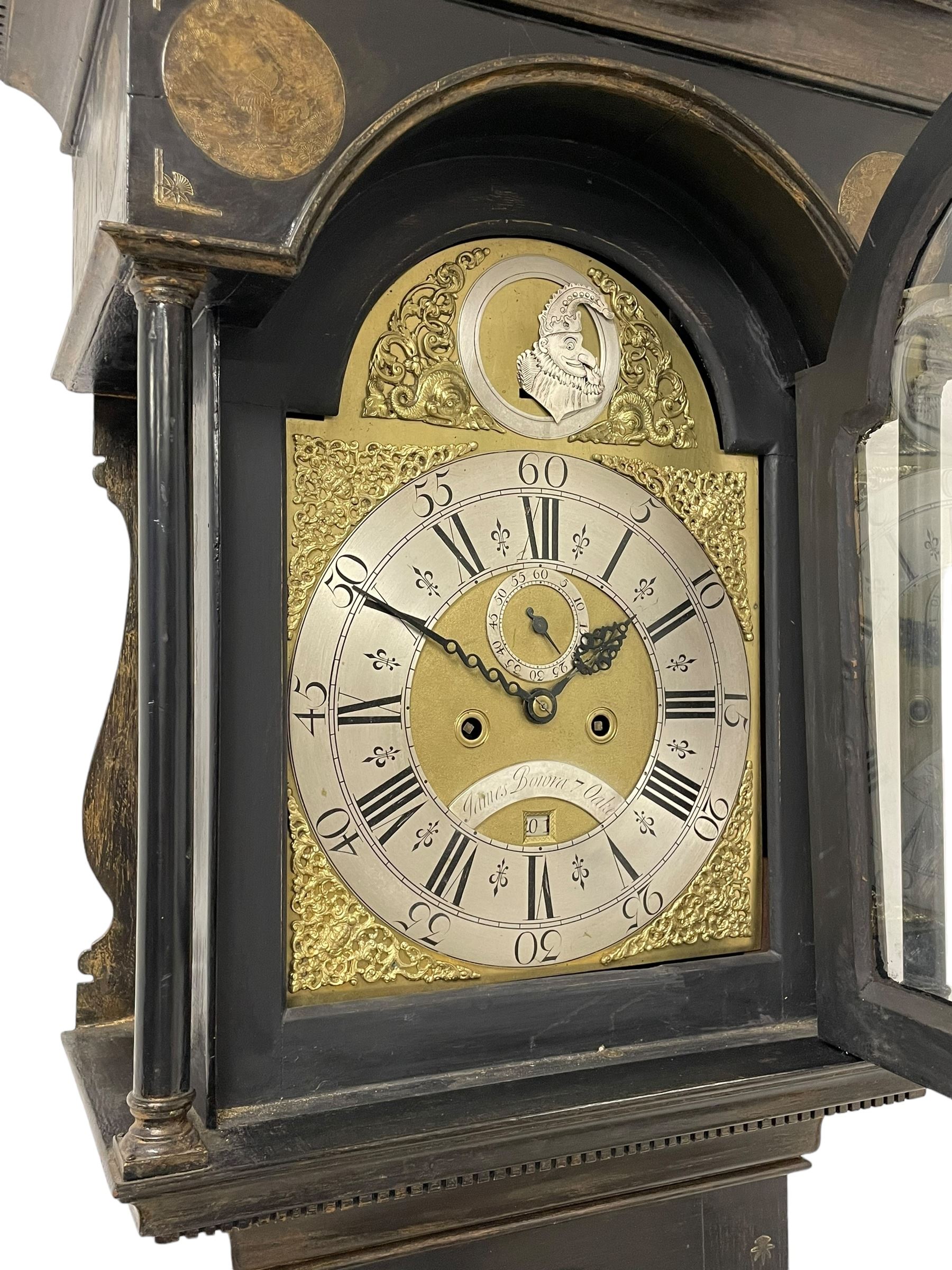 James Bowra of Sevenoaks Kent - 18th century 8-day ebonised longcase clock with gilt decoration c1740, with a flat top, dentil moulding beneath and shaped back splats, break arch hood door flanked by plain pilasters with wooden capitals, long trunk with a curved topped door, on a square plinth with canted corners and raised on a moulded base, brass dial with cast spandrels and a silvered 'Punch' automata to the arch, matted dial centre with seconds ring and date aperture, silvered chapter ring with Roman numerals, five minute Arabics, minute and quarter hour tracks, with matching steel hands and silvered makers name plate, rack striking movement with a recoil anchor escapement, striking the hours on a bell. With weights and pendulum.