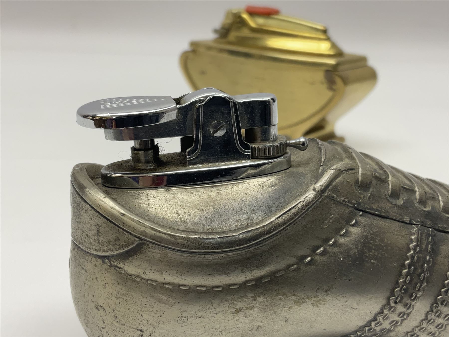 Ronson gilt metal table lighter, together with a silver-plate table lighter in the form of a football boot