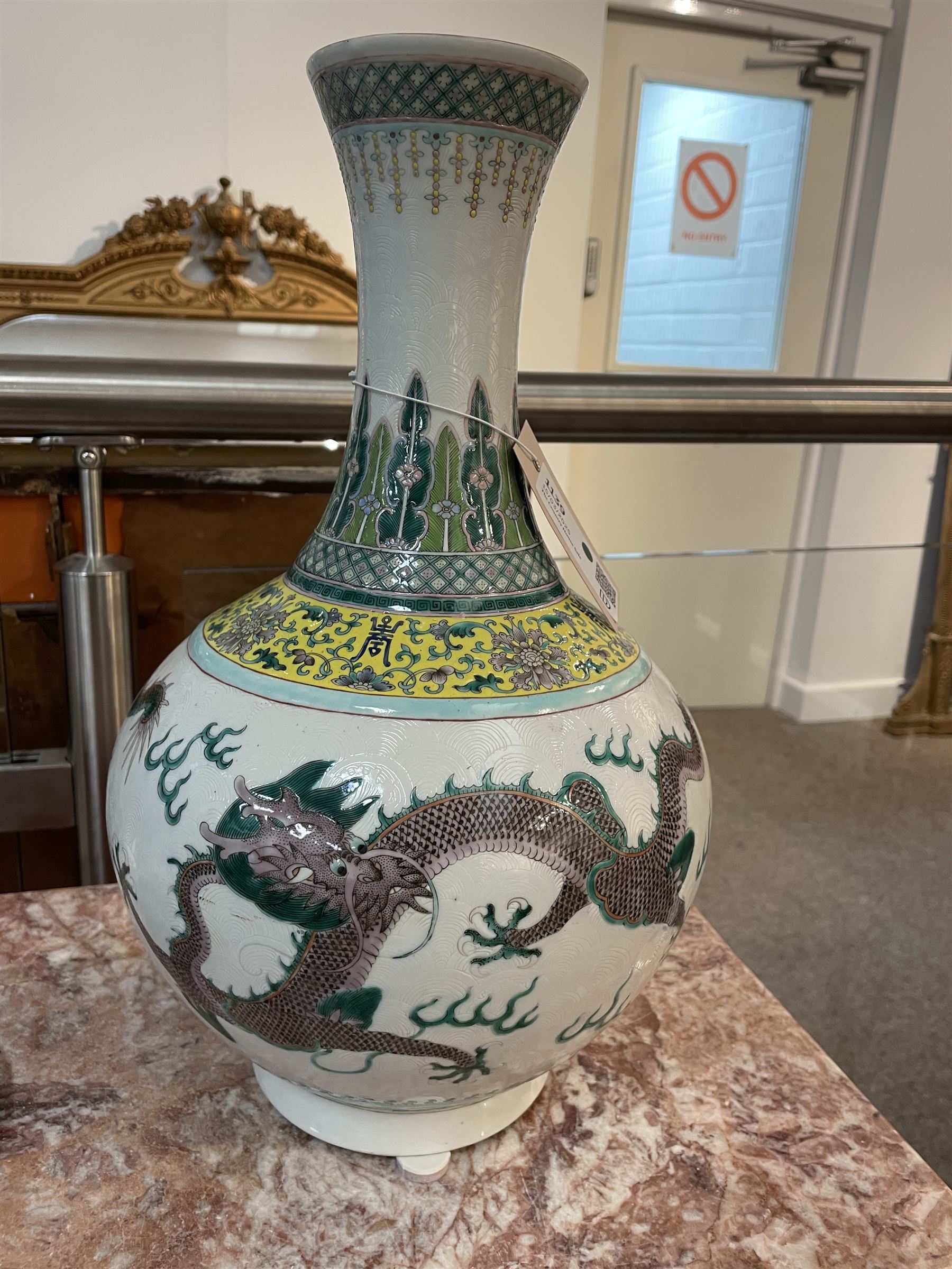 Pair 20th century Chinese famille verte bottle vases, each decorated with green and purple dragons chasing pearls amidst auspicious flames, the neck with yellow and green stylised foliate and cell borders, and the white glazed body incised throughout with fan shapes, each with red character mark beneath flanked by green dragons, H38cm

