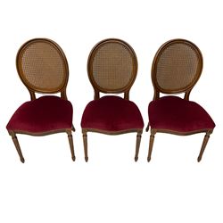 Set six French style walnut finish dining chairs, oval cane bergere backs over serpentine seats upholstered in red, flower head carved fluted supports