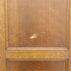 Edwardian oak glazed cabinet, moulded cornice above a panelled front and sides, fitted with lead glazed doors enclosing shelved interior, left side full length cupboard converted to enclose a gun cabinet, on a plain plinth base 