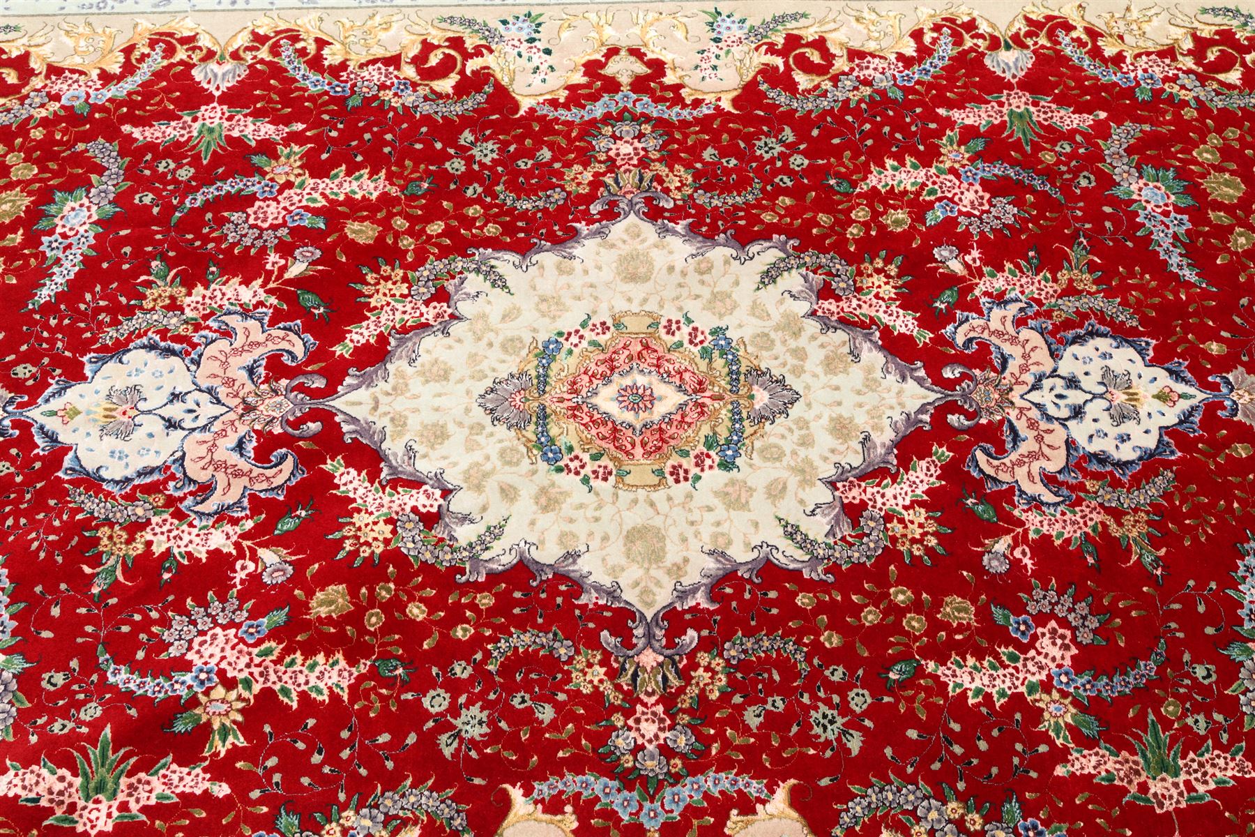 Fine Persian silk inlaid crimson ground Tabriz rug, the shaped field decorated with a central foliate pole medallion filled and surrounded by finely knotted floral motifs and trailing foliage, the cyan guard stripe with bold festoons and palmette motifs