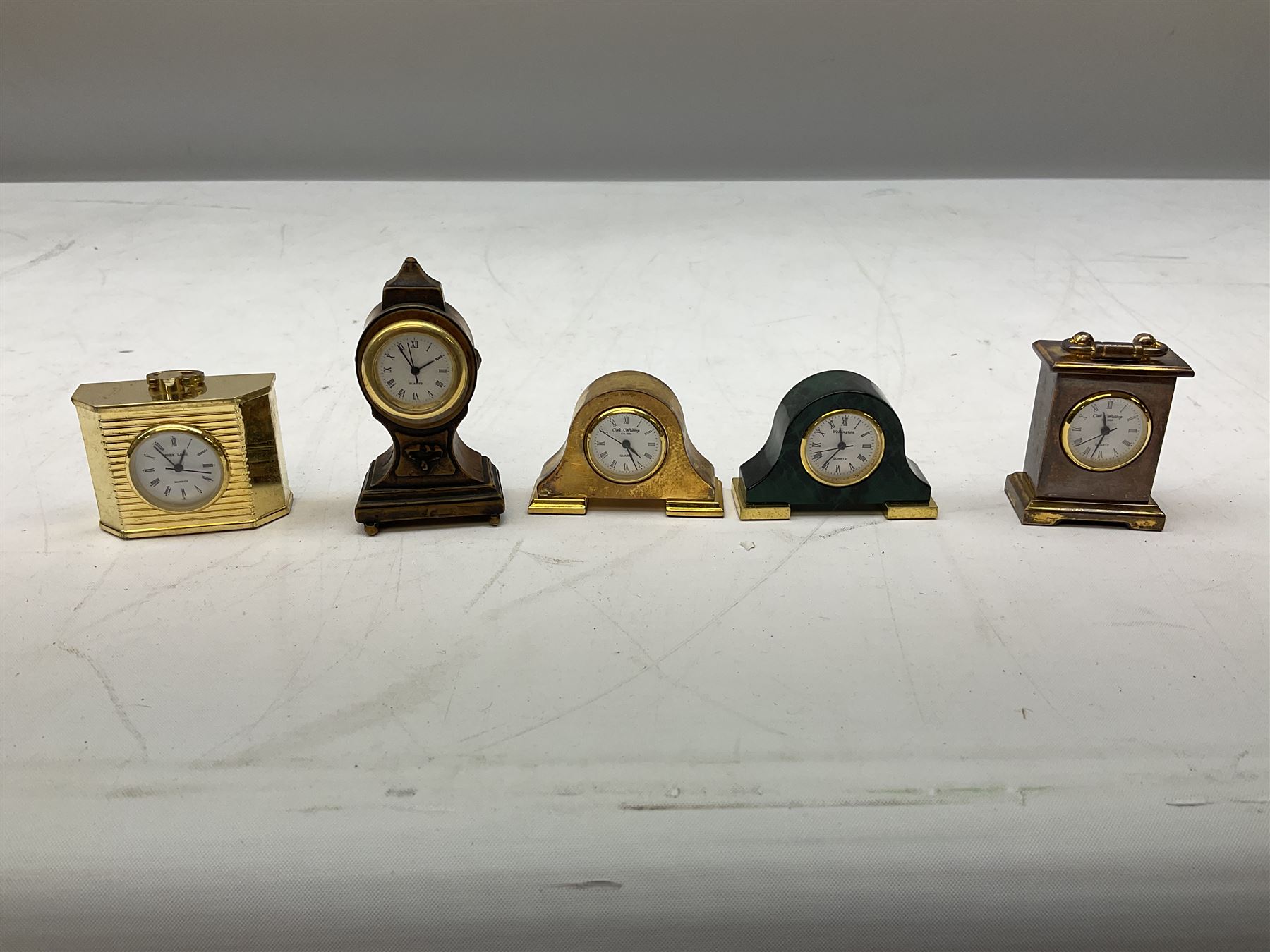 Collection of miniature clocks, predominantly with quartz movements, to include example modelled as an armchair, Edinburgh crystal glass example, clock modelled as a flower, sewing machine etc