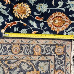 Persian Kashan carpet, navy field with an all-over design of scrolling vines, palmettes and rosettes in gold and pale blue, enclosed by multiple floral borders with stylised palmette motifs, originating from Central Iran