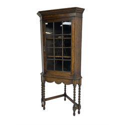 Early to mid-20th century oak corner display cabinet, projecting cornice over astragal glazed door, on spiral turned supports joined by stretchers