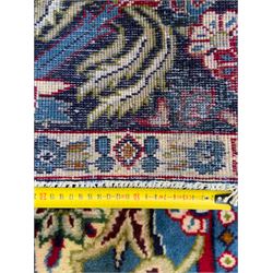 Central Persian Isfahan Carpet, hand-knotted, featuring a bold central rosette medallion on a rich red field, flanked by stylised floral sprays, scrolling foliage and mythical animals, within a broad indigo border decorated with alternating cartouches and flowerheads