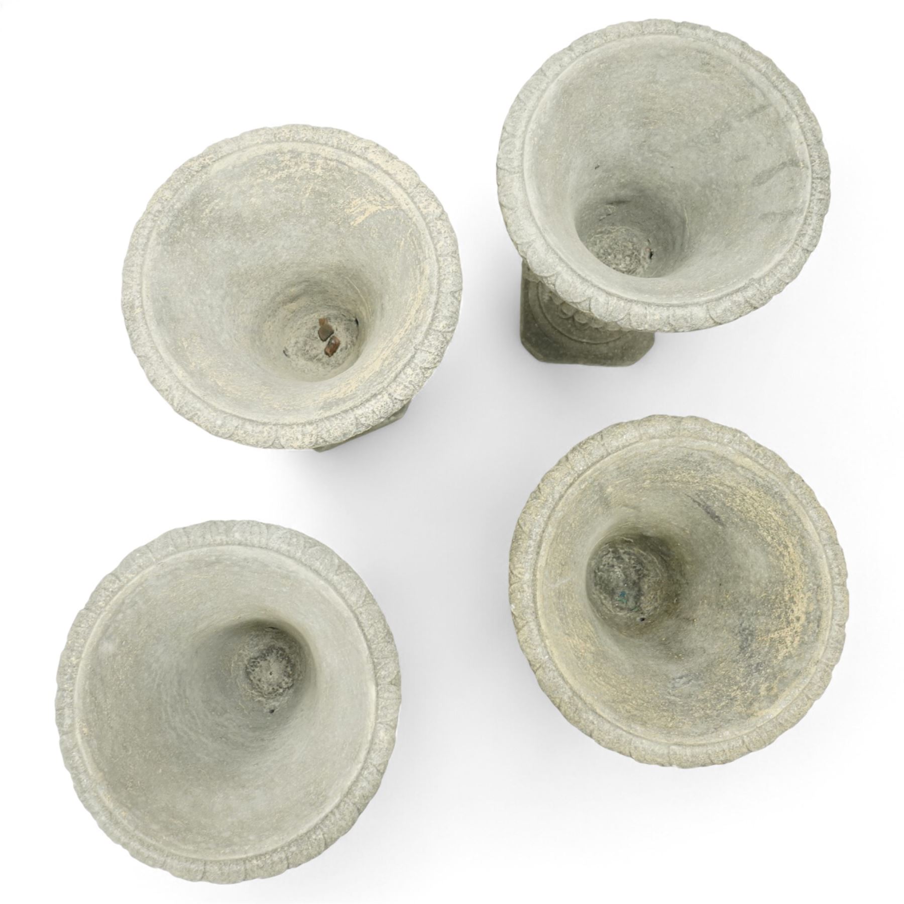 Late 20th century set of four composition stone campana urns, each with everted rim over acanthus and mask relief decoration, tapering to a fluted socle on square plinth base