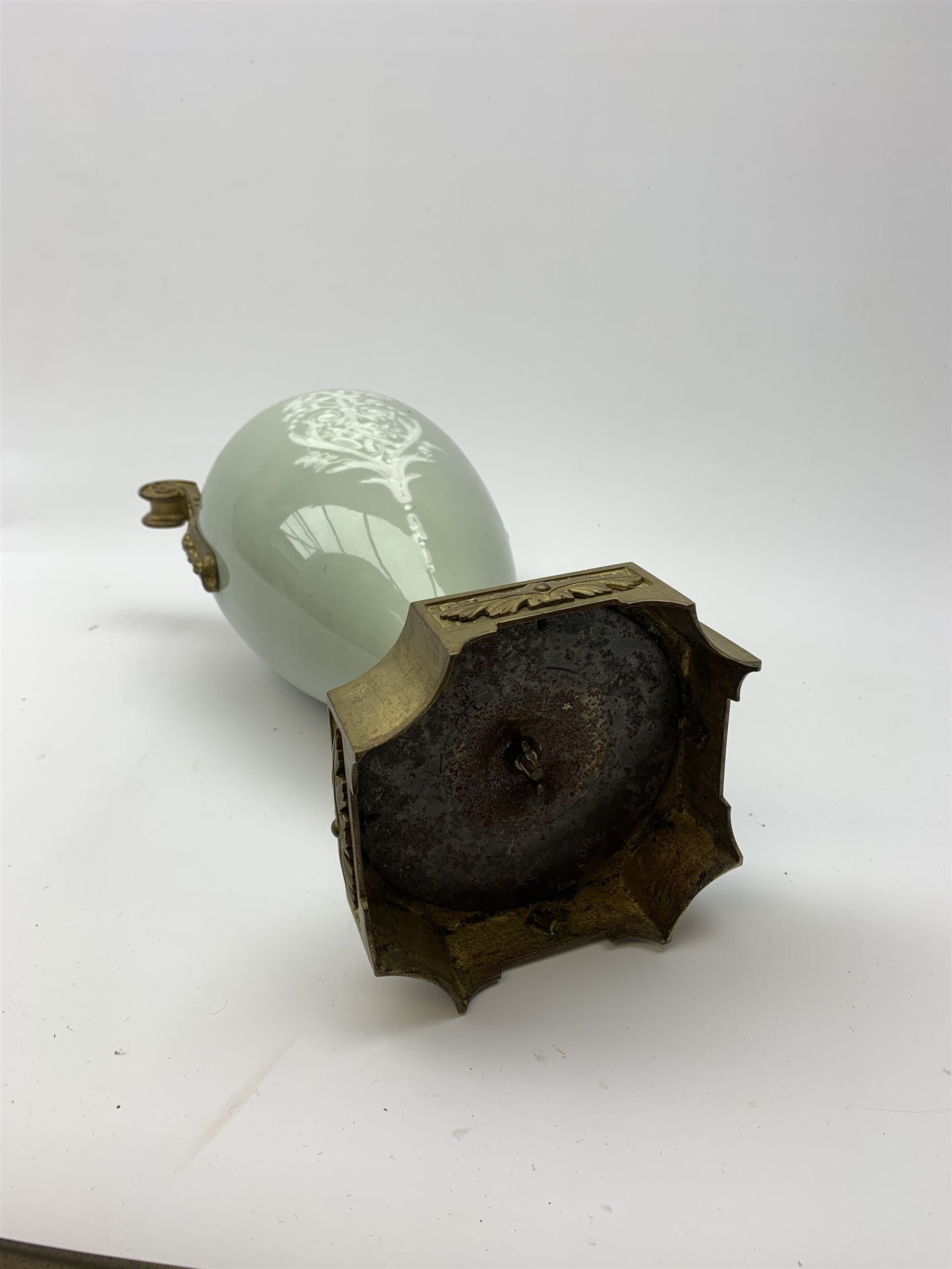 A pate sur pate celadon green vase, of baluster form decorated with a classical female figure to one side, and floral swag with ribbon and musical trophy to the other, with twin gilded scroll handles, and raised upon a gilded base, overall H38.5cm. 