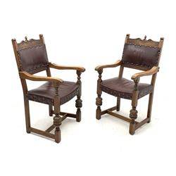 Pair 20th century oak armchairs, shaped cresting rail carved with flower heads, dished seats and backs upholstered in studded leather, turned cup and cover supports joined by stretchers, W54cm (total width)