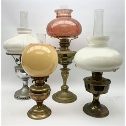 Four oil lamps, each with chimney and shade, the tallest H66cm including chimney