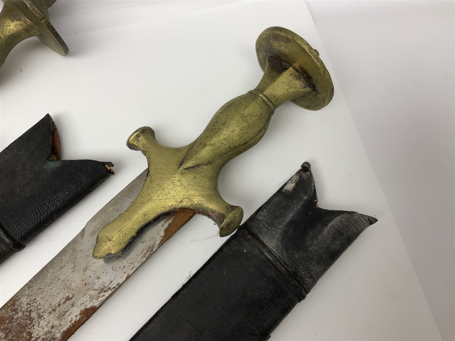 Four Indian tulwar swords; three with cast brass hilts and one with iron hilt; longest blade 81cm; all with scabbards (4)
