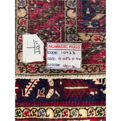 Northwestern Persian Heriz hand-knotted runner, dark indigo field with a series of linked stepped medallions in madder red, ivory, and green, flanked by angular floral motifs, within a madder red border of stylized rosettes and geometric vine motifs 405cm x 95cm