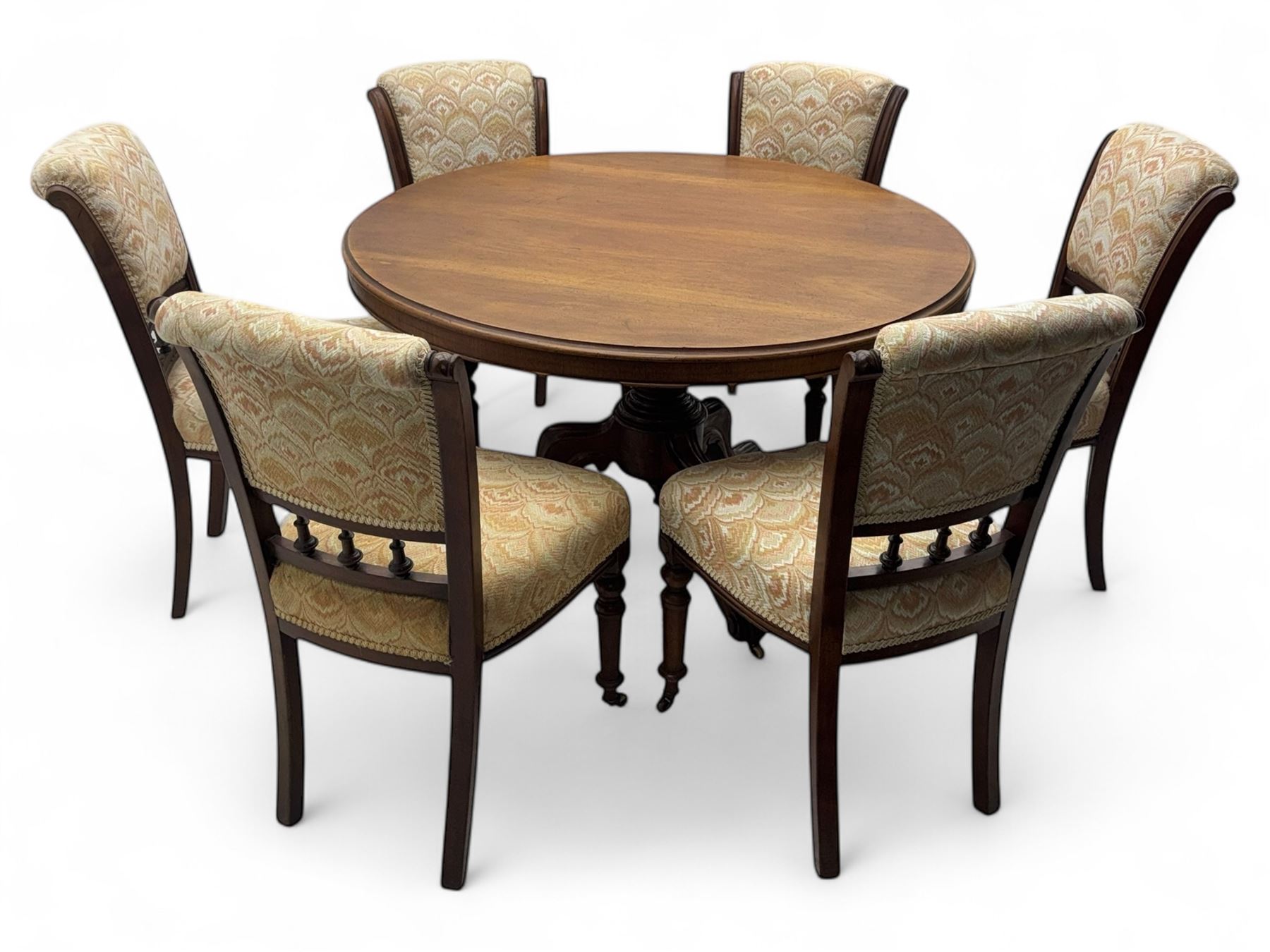 Victorian mahogany centre table, circular top above turned pedestal, terminating on three cabriole legs with scroll feet on porcelain castors, and six scroll carved upholstered dining chairs, with cushion and spindle turned backs, centre table  118x74cm, dining chairs 89x46x50cm