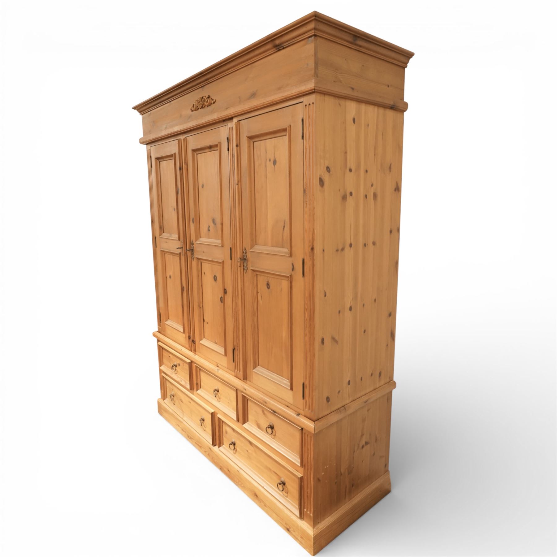 20th century pine wardrobe with drawer base, moulded cornice over three fielded panel cupboard doors enclosing hanging compartments, the base fitted with three short and two long drawers with brass ring handles, raised on a plinth base