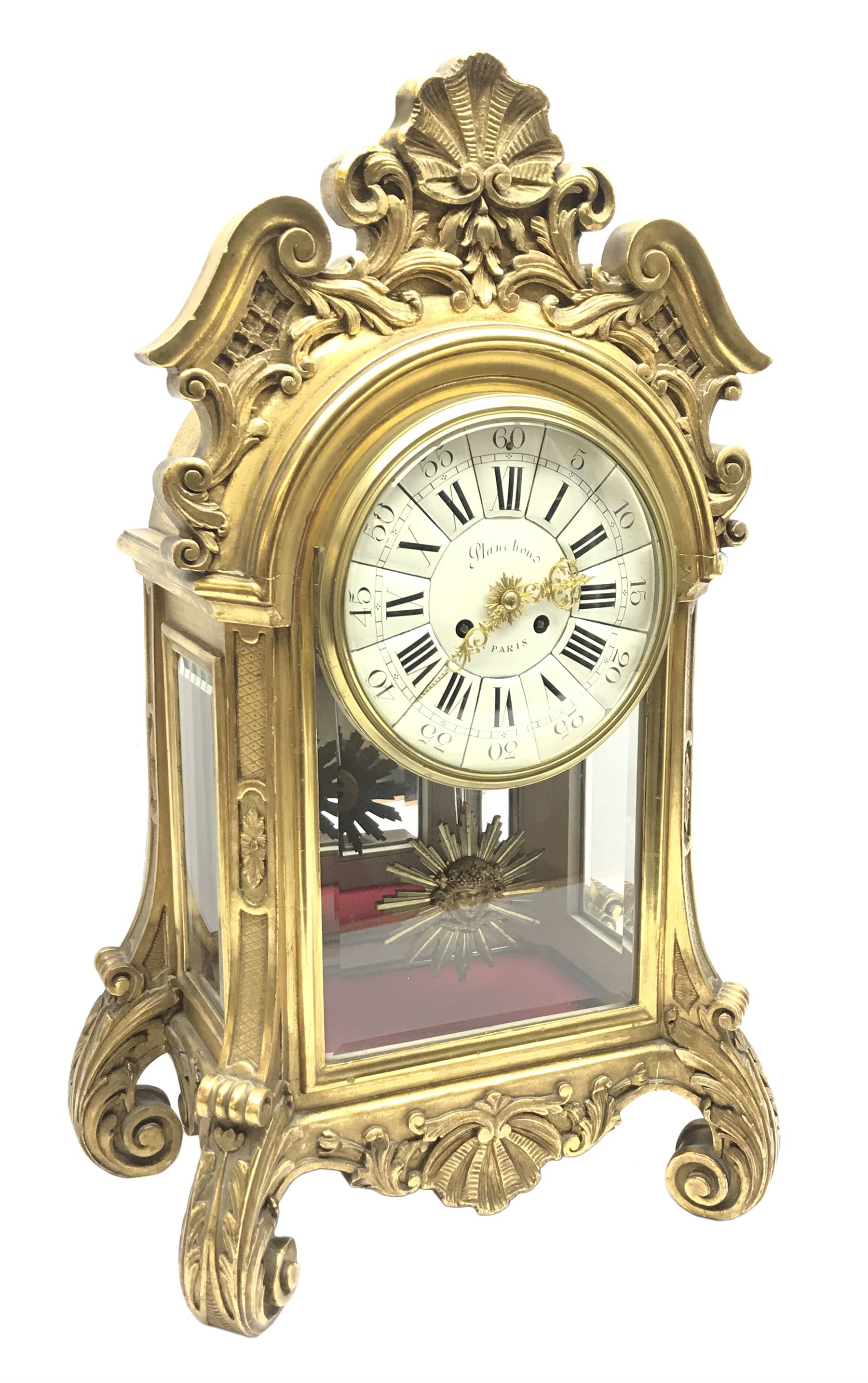 20th century French clock by Planchon Paris, decorative gilt case with shell pediment set on scrolled leafage, circular porcelain segmented dial with Roman and Arabic numerals, bevel glazed front and sides with mirrored interior, acanthus carved feet with scrolled terminals, shell to apron to match, eight day movement striking the hours and half on bell, sunburst and mask cast pendulum, with key, W36cm, H59cm, D21cm
