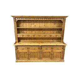Large traditional pine dresser, projecting reeded cornice over two tier plate rack fitted with eight spice drawers, flanked by rope-twist upright pilasters and foliate carved scrolled corbels, the base fitted with four drawers and two double cupboards 
