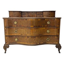 Late 19th century continental oak commode, serpentine fronted with parquetry and crossbanded decoration, the raised superstructure back fitted with a central bank of five recessed drawers flanked by concave drawers, above three full-width drawers with brass ring handles, raised on cabriole supports