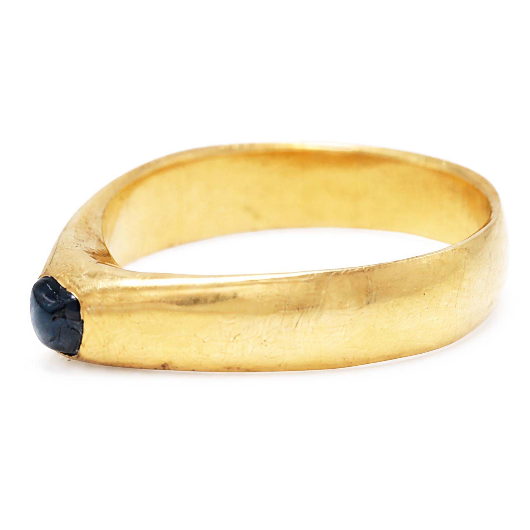 Medieval gold sapphire stirrup ring, circa. 1150-1500, the hoop of ‘D’ shaped cross-section, with raised triangular shaped bezel centred at the apex with a cabochon sapphire