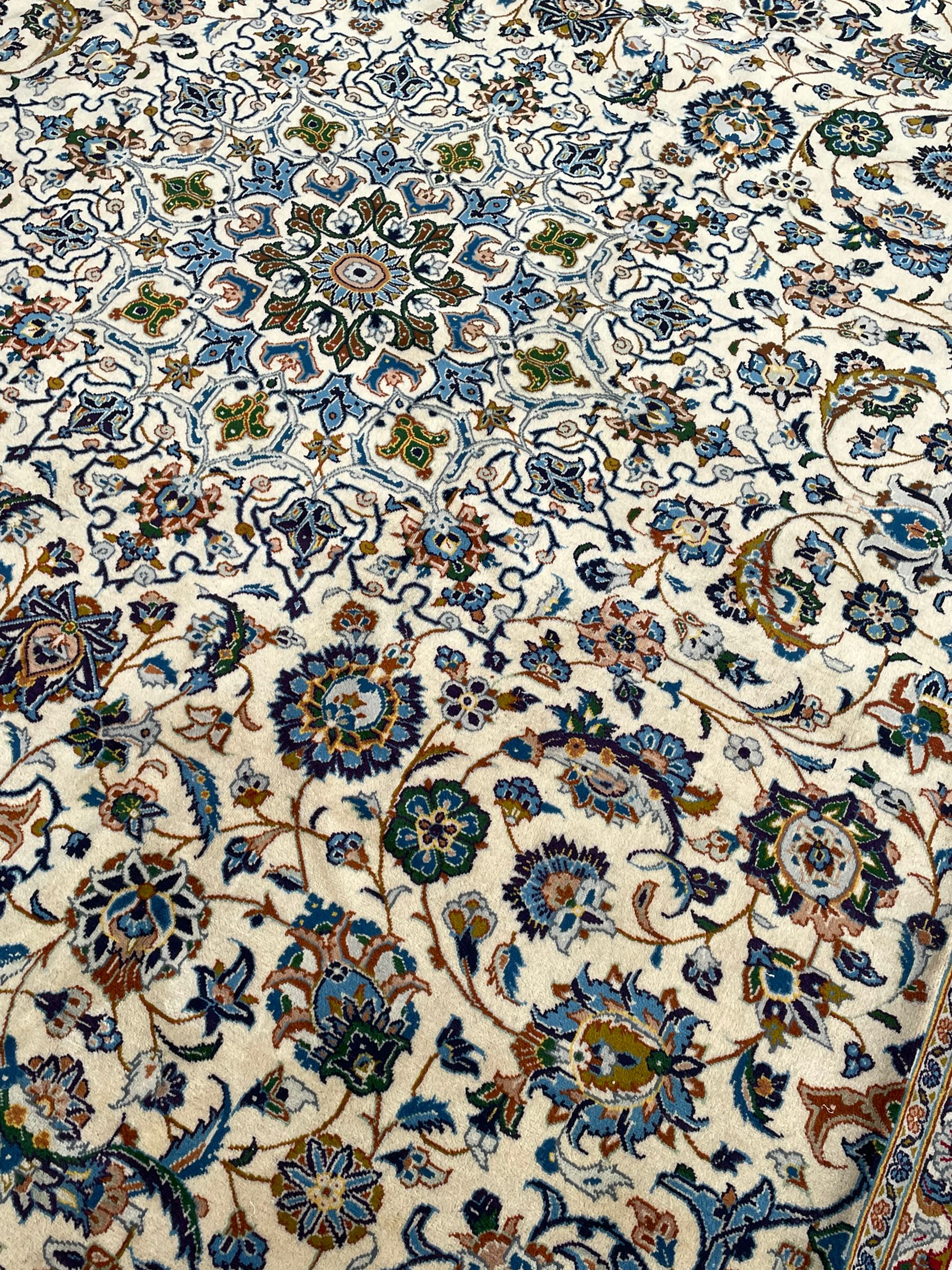 Persian Kashan ivory ground carpet, the interlaced foliate medallion surrounded by trailing plant motifs interlaced with scrolls, the guarded border with repeating stylised flower heads