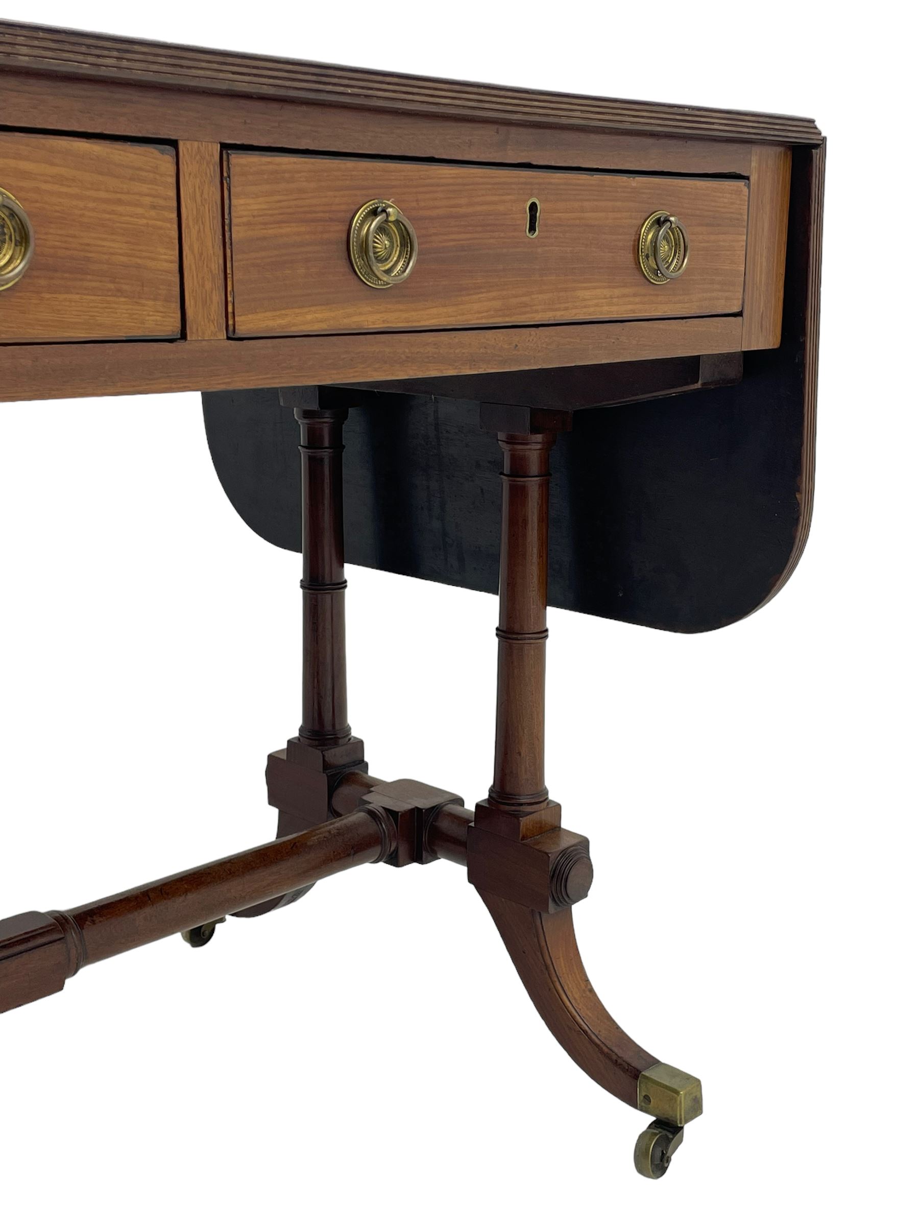 George III mahogany sofa table, rectangular drop-leaf top with reed moulded edge and rounded corners, fitted with two frieze drawers and two opposing false drawers, quadruple collar turned pillar supports on turned and block platforms, splayed and moulded supports with brass cups and castors 