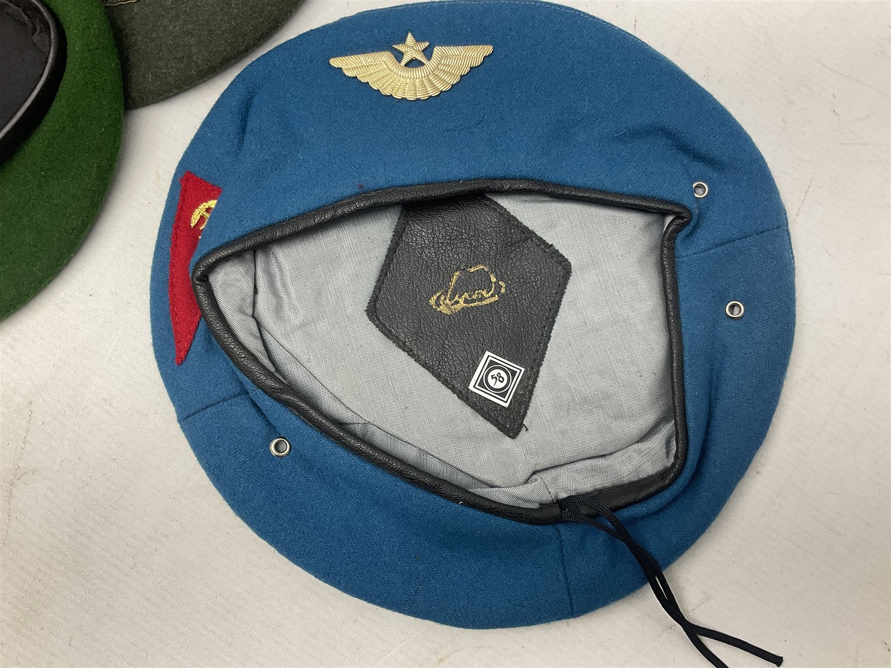 Four paratrooper berets - Russian, Italian, British and Foreign Legion; all with badges (4)
