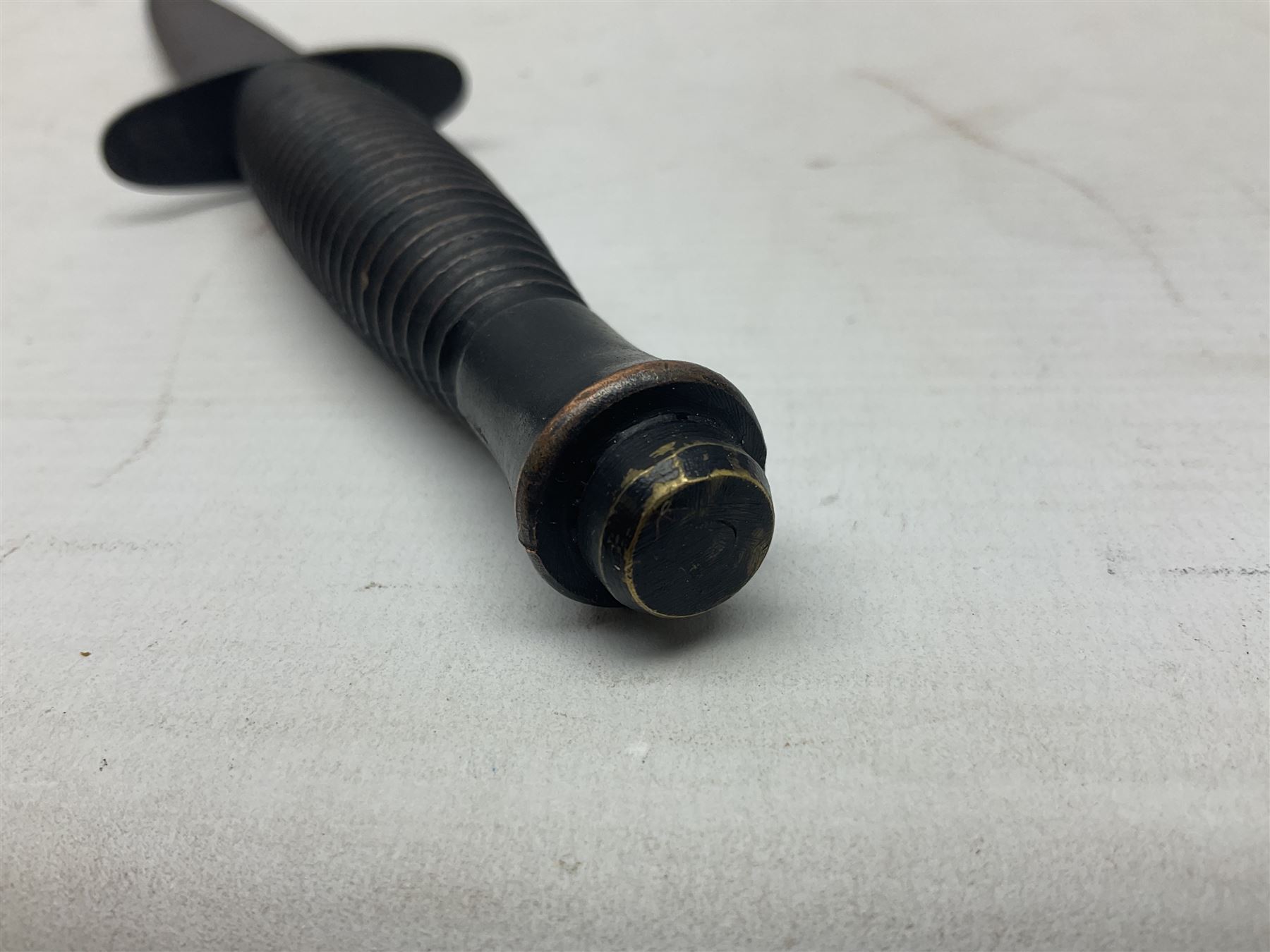 Third Pattern Commando Knife or Dagger with 17.5cm flattened diamond section blade and regulation black painted ribbed copper hilt with brass pommel nut; stamped William Rodgers Sheffield England to the cross-piece; in black painted brass mounted leather scabbard L34.5cm overall