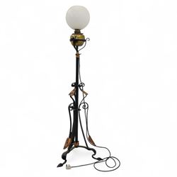 Early 20th-century Art Nouveau style standard lamp, wrought iron scrolled tripod base with copper foliate terminals supporting a brass oil reservoir surmounted by an opaline glass globe shade with spiral patterning, wired for electricity, untested 
