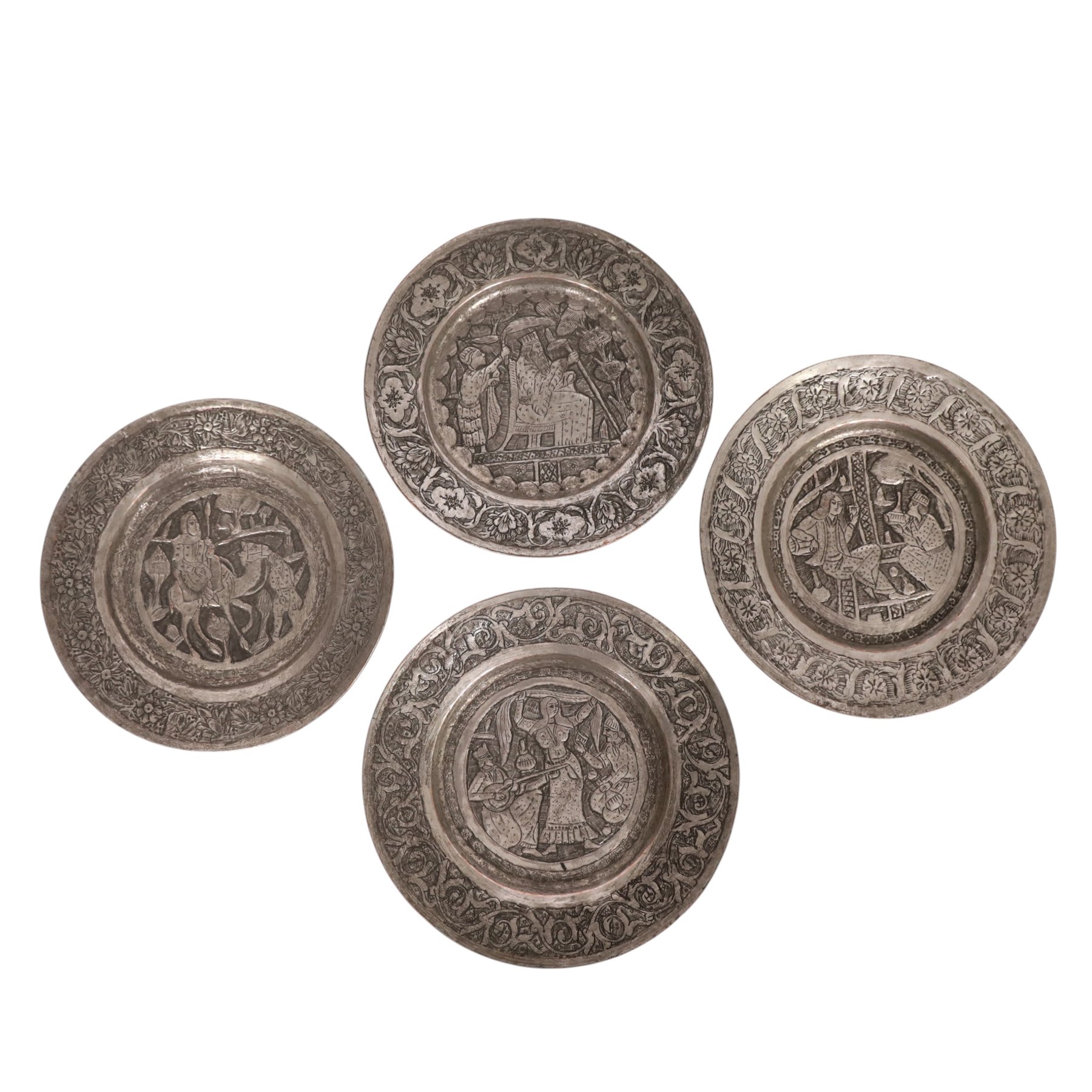 Set of four Persian silvered copper plates, decorated in relief, the central panel depicting figures in various scenes with a floral boarder, D17cm