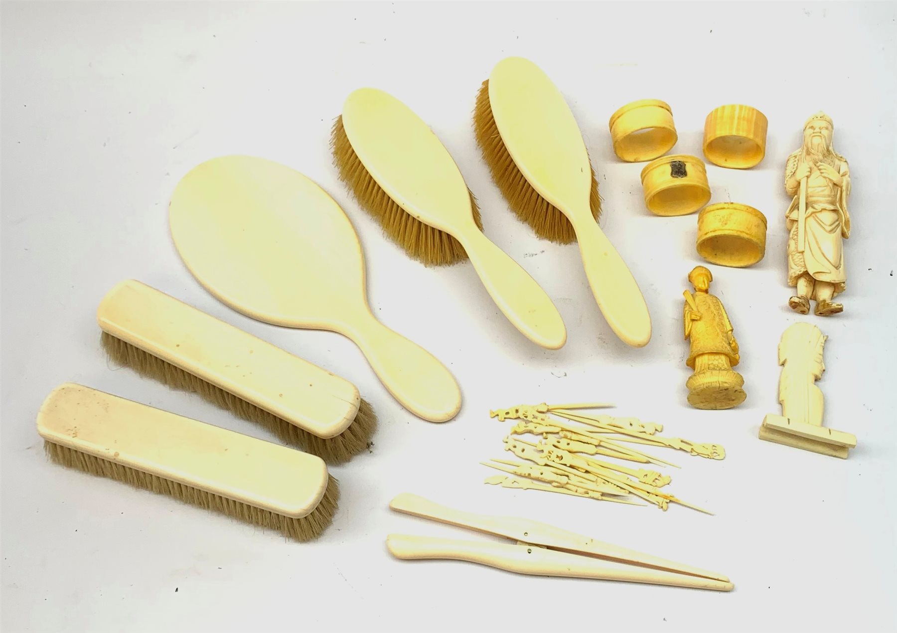 A selection of assorted ivory and bone items, to include a Japanese okimono modelled as a sage, four napkin rings, three with hallmarked silver cartouches, a early 20th century dressing table set, comprising hand held mirror, two hair brushes, two clothes brushes, and glove stretchers, plus a number of picks with carved figural terminals. 