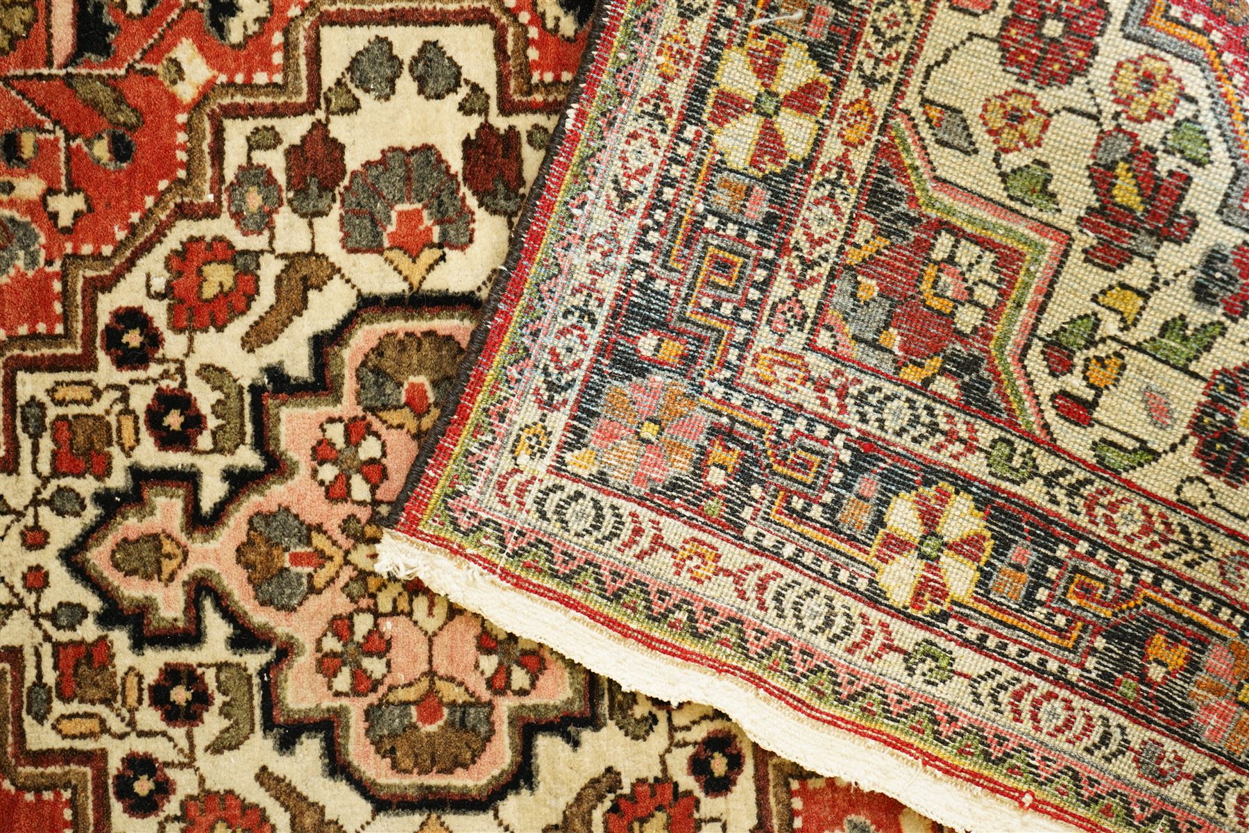 Persian Heriz-style rug, bold geometric octagonal medallion, rich red field with ivory spandrels, dark navy border, rosettes and vines; inner guards with repeating patterns 