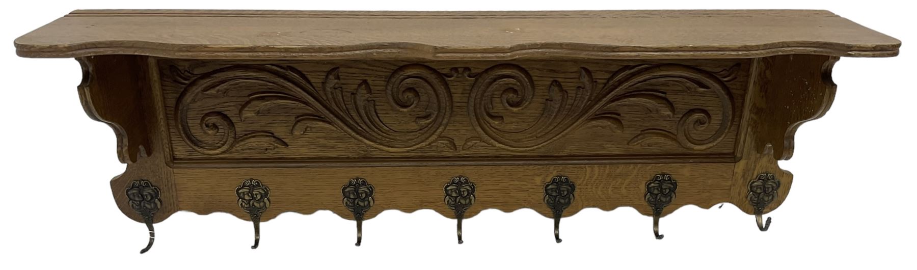Oak wall hanging coat rack, shape lintel over panelled back carved with foliate S-scrolls, fitted with seven hooks