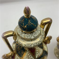 Pair of Vienna style twin handled urns and covers, decorated with figural scene on green, red and white ground with gilt highlights, stamped with beehive mark beneath, H25cm