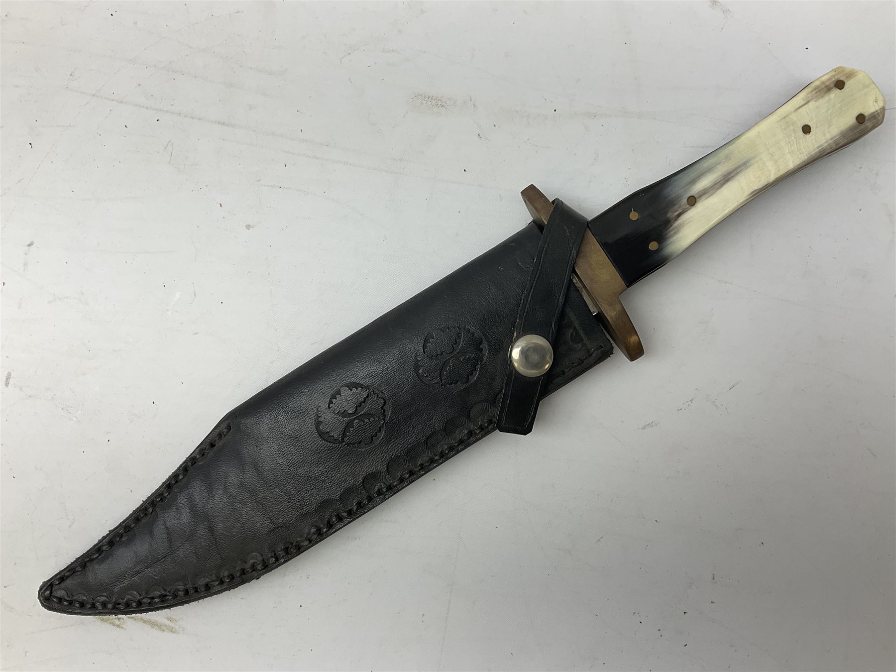 Large Bowie knife the 21cm steel blade marked J.E. Middleton & Sons Rockingham Street Sheffield with brass cross-piece and polished horn grip scales; in leather sheath L36cm overall