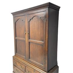 George III oak livery cupboard, projecting moulded cornice over two panelled doors, the upper panels within stepped ogee and arched moulded frame, the interior fitted with a single row of wooden hooks, two short and one long drawers, on bracket and return skirted base 