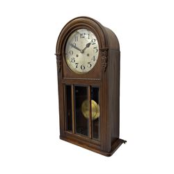 German HAC “ting tang” quarter striking wall clock in a round arched oak case with applied carving and beadwork, glazed door with a visible pendulum and silvered 24-hour dial with Arabic numerals and steel spade hands,  8-day spring driven movement striking on gong rods.

