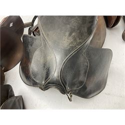 Collection of nine saddles, mainly havana leather to include a racing saddle and a Goodwin saddle, some with stirrups and leathers 