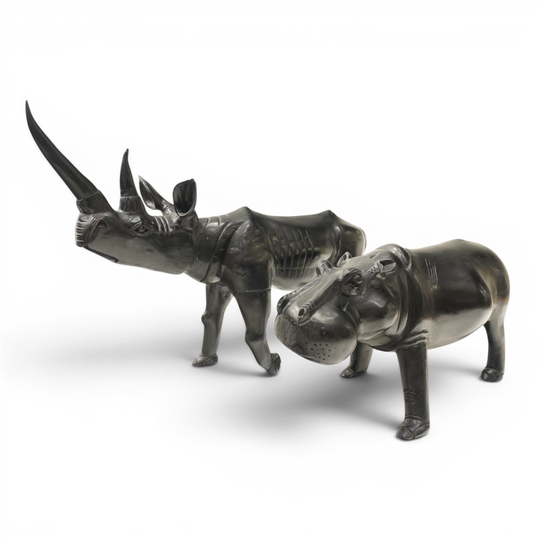 African carved hardwood ebonised figures of a rhinoceros and hippopotamus, each with stylised incised detail and polished dark finish, largest H 61cm, W 91cm)