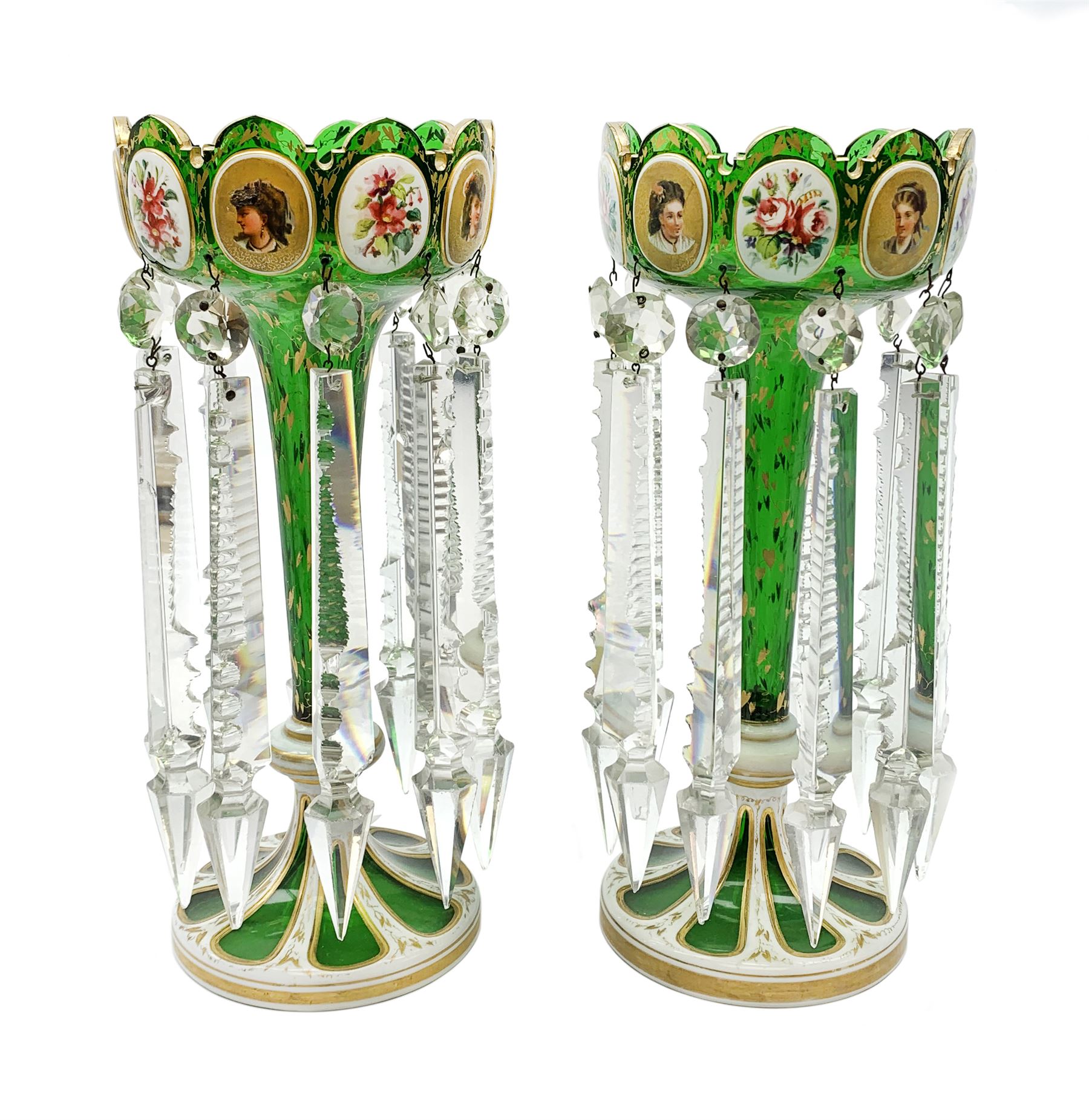 Pair of 19th century Bohemian green glass lustres, the castellated bowls decorated with overlaid panels of flowers and female portraits, upon tapering stems and overlaid spreading feet, heightened throughout with gilt, each supporting ten prismatic drops, H35cm