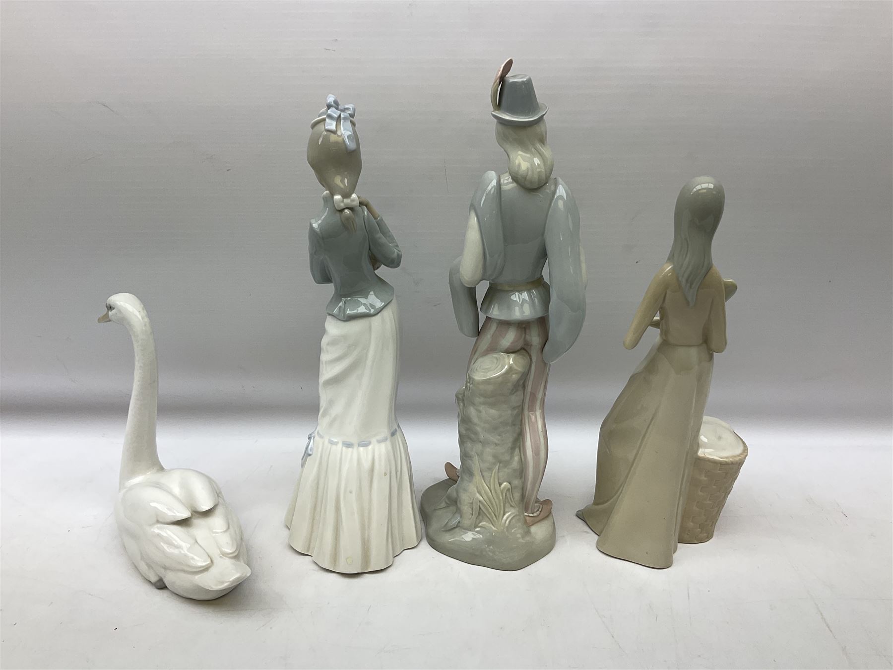 Lladro 'Walk With the Dog' figure no. 4893, together with Lladro swan figure, Porceval figure of a gentleman with a bird perched upon his hand and a further of a lady with flowers beside a basket, all with marks beneath, tallest H40cm