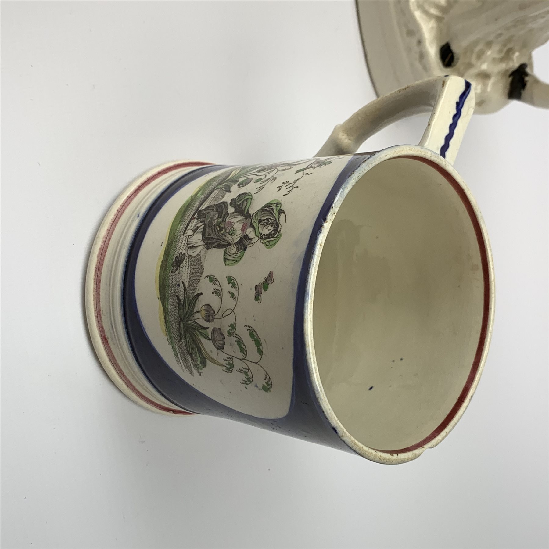 An early Victorian earthenware frog or surprise mug, decorated with printed and overpainted figural panels, H11cm, together with a 19th century child's plate detailed with a figural scene and inscribed Father Matthew administering the total abstinence pledge, 17.5cm, and a Staffordshire flat back figure seated upon a horse, H33cm. 
