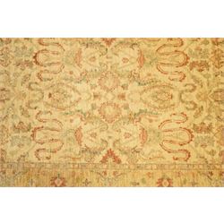 Ziegler design hand-knotted wool rug, the central field with symmetrical scrolling floral motifs in muted tones of beige, sage green, and terracotta, within a conforming border, all on a soft ivory ground
