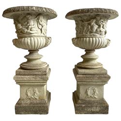 Large pair of cast stone three-piece Grecian urns, the moulded rim over body decorated with putti, horses and trees, gadrooned underbelly with faun masks, on stepped and moulded circular footed base, the square plinth with moulded upper edge, each side decorated with laurel wreath, moulded skirted base