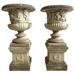  Large pair of cast stone three-piece Grecian urns, the moulded rim over body decorated with putti, horses and trees, gadrooned underbelly with faun masks, on stepped and moulded circular footed base, the square plinth with moulded upper edge, each side decorated with laurel wreath, moulded skirted base