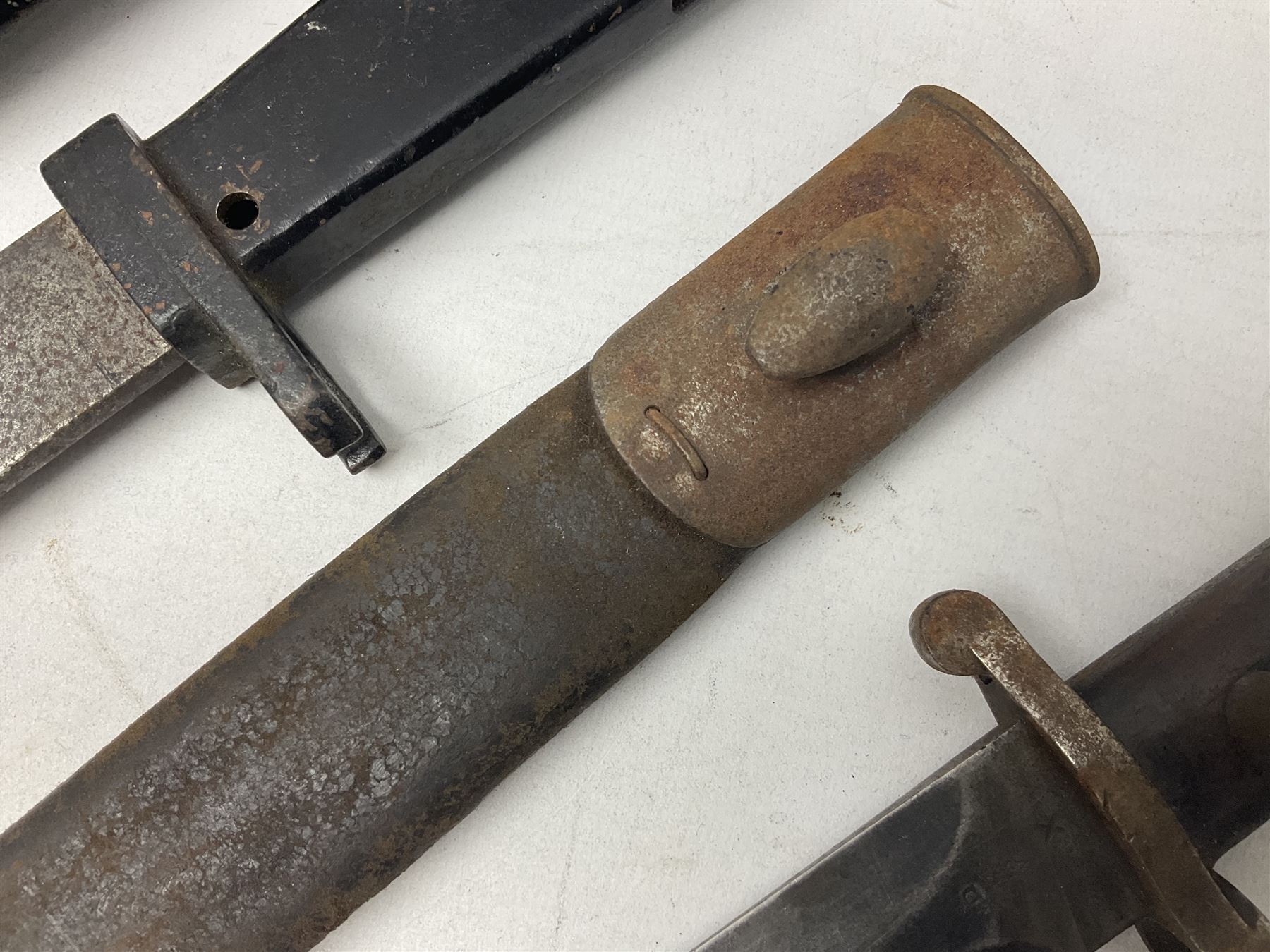 British No 7 MKI knife bayonet with 20cm single edged fullered clipped point blade;  blackened steel, large muzzle ring cross-guard; blackened swivelling pommel marked 'F5H'; red Tufnol composite grips; in blackened steel scabbard L33cm overall; British Pattern 1888 bayonet with scabbard; and German Ersatz bayonet with scabbard (3)