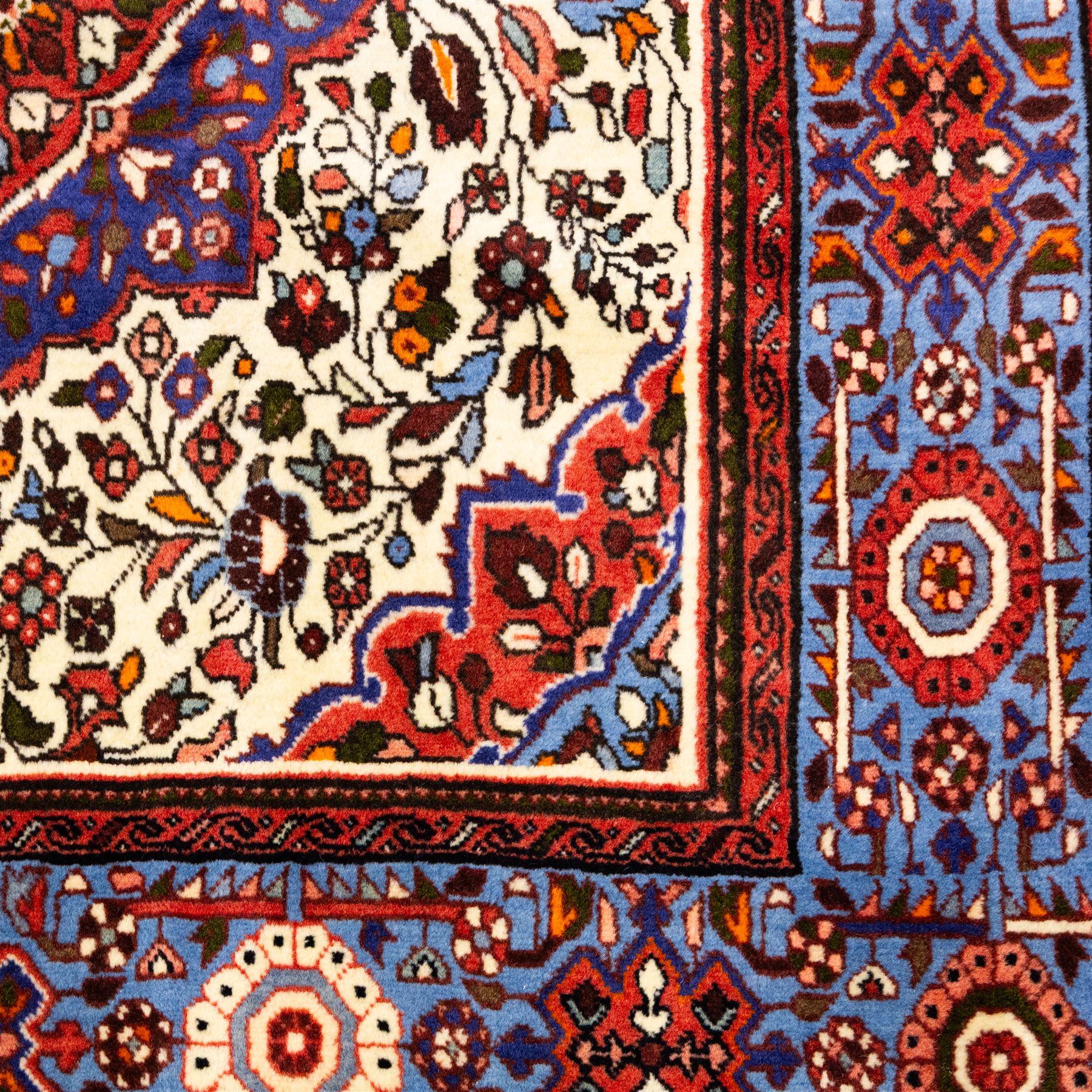 West Persian Hamadan hand-knotted rug, ivory field decorated with a repeating lattice of stylised geometric medallions interspersed with small floral motifs and angular vine ornament enclosed by a sky blue border of stylized rosettes and geometric devices between multiple guard stripes, with cotton fringe ends  