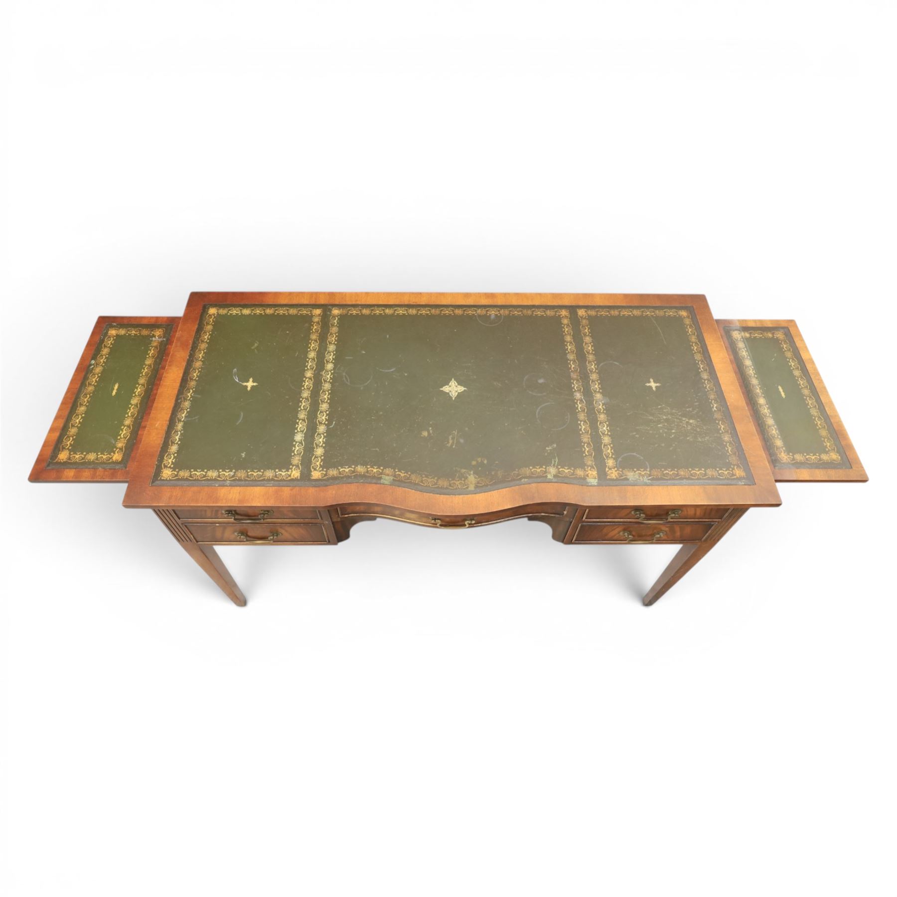 Regency style mahogany writing desk, serpentine front tooled green leather inset, slides to either side, central frieze drawer, flanked by a bank of two drawers, square tapering supports