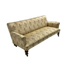 Victorian three seat sofa, upholstered in floral and scrolling foliate patterned fabric with sprung seat, raised on turned supports with castors